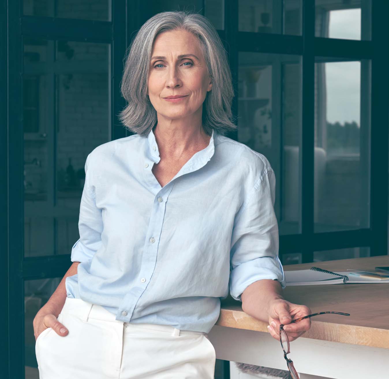 Older woman leaning on a table.