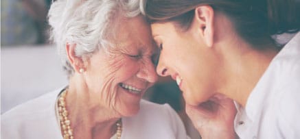 Older mother and daughter touching foreheads.